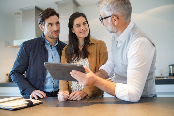 Couple with furniture sales person looking at tablet with furniture options